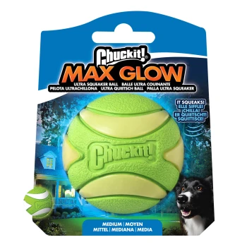 Chuckit! Max Glow medium ultra piepbal hondenspeelgoed dat groen gloeit met verpakking en blije zwart-witte hond.