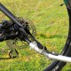 Nahaufnahme des Hinterrades eines Fahrrads, das die Scheibenbremse, die Kette und einen schwarzen Riemen zeigt, der den Rahmen am Rad sichert.
