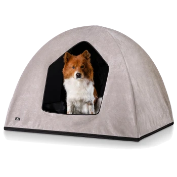 Ein flauschiger braun-weißer Hund sitzt in einem gemütlichen, hellgrauen Haustierzelt mit einem schwarzen Innenraum, das einen dreieckigen Eingang hat.