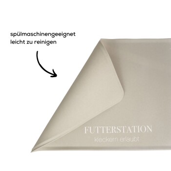 Eine hellbeige Futtermatte für Haustiere mit dem Text 'FUTTERSTATION kleckern erlaubt', was darauf hinweist, dass sie spülmaschinenfest und leicht zu reinigen ist.