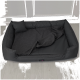 Ein grauer Weimaraner-Hund ruht auf einem braunen Haustierbett in einem modernen Wohnzimmer mit einem dunklen Sofa und einem Holztisch.