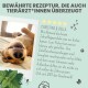 Ein glücklicher Hund, der auf einem Bett liegt und seine Zähne zeigt, mit einem Testimonial von Christine & Bella, das ein Zahnpflegeprodukt lobt.