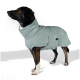 Ein brauner und schwarzer Hund, eingewickelt in ein weiches, hellblaues Handtuch, das von der Kamera abgewandt ist, vor einem schlichten weißen Hintergrund.
