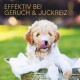 Ein flauschiger, hellfarbener Welpe sitzt in einer Metallschüssel, die mit Blasen gefüllt ist, leckt sich die Nase, mit dem Text "EFFEKTIV BEI GERUCH & JUCKREIZ" darüber.