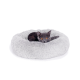 Ein graues Kätzchen mit leuchtend orangefarbenen Augen, das in einem flauschigen, runden grauen Haustierbett entspannt.