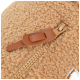 Gros plan sur un lit pour animal beige et moelleux avec une fermeture éclair et une languette en cuir marron, mettant en valeur sa texture douce.