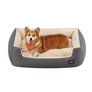 Ein glücklicher Corgi mit einem orangefarbenen Halstuch ruht sich bequem in einem plüschigen, grauen Hundebett mit einem weichen cremefarbenen Innenraum aus.