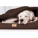 Ein weißer Hund ruht sich bequem in einem braunen Haustierbett aus, teilweise von einer Decke bedeckt, mit einem sichtbaren "tierlando"-Etikett auf dem Bett.
