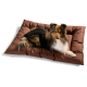 Ein flauschiger Collie-Hund, der auf einem braunen gepolsterten Haustierbett ruht, auf dem das Wort "HUNTER" gestickt ist.