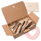 Offene Kraft-Geschenkbox mit Papierstreu und mehreren halbierten Geweih-Kausnacks; Deckel zeigt 'FOURLEGS'.