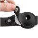 Hand öffnet den Druckknopf des schwarzen Lederhalsband-Trackerhalters und legt das weiße runde Trackinggerät frei.
