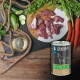 Dose LIEBESGUT-Hundefutter mit der Aufschrift 'Pferd für Hunde' neben rohem Pferdefleisch auf einem Brett, Karotten, Zucchini und einer kleinen Schale Öl.