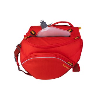 Roter Hunderrucksack mit einer teilweise sichtbaren Wasserflasche in der Fronttasche, mit dem Markennamen 'RUFFWEAR' an der Seite.