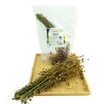 Getrocknete Leinsamenbündel auf einem Holztablett, mit einer klaren Tüte mit der Aufschrift "Flachshaaren", die weitere getrocknete Leinsamen enthält.