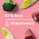 Bild von Zutaten für Tierfutter mit Brokkoli, Salat und Rindfleisch, mit dem Text "87% Rind" und "Vitaminreich" auf einem rosa Hintergrund.