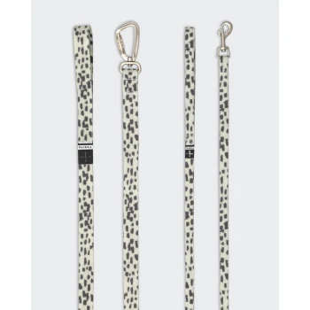 Eine stilvolle Hundeleine mit einem cremefarbenen Hintergrund und schwarzen Leopardenflecken, die einen stabilen Metallclip und ein Markenlabel zeigt.