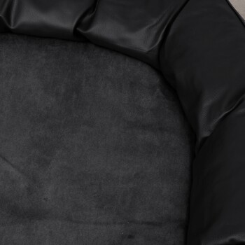 Zwei Dalmatiner entspannen sich auf einem schwarzen Haustierbett in einem gemütlichen Raum mit einem Holzofen und blicken durch ein Fenster auf eine verschneite Landschaft.