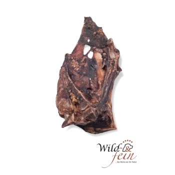 Ein natürlicher Hundekauartikel aus einem großen, unregelmäßig geformten Stück Knochen, mit dunklen und hellen Texturen, mit dem Logo "Wild & fein" am unteren Rand.