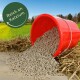 Roter Eimer, der braune Futterpellets auf Stroh auf einem Feld verschüttet, grünes Siegel mit Aufschrift 'Reich an Kalzium'