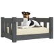 Ein schwarz-weißer Hund ruht auf einem stilvollen grauen Holzhaustierbett mit einem beigen Kissen, das Komfort und Design zeigt.