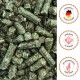 Nahaufnahme grünlich-brauner Haustierfutterpellets mit deutschen Etiketten: "Hergestellt in Deutschland", "Ganzjährig zu füttern" und "Aus hochwertigen Rohstoffen".