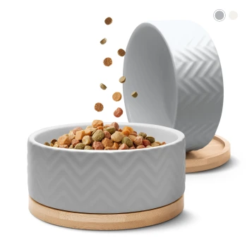 Eine stilvolle graue Futterschale für Haustiere mit Zickzackmuster, gefüllt mit buntem Futter, und einer anderen Schale, die schräg daneben steht und mehr Futter fallen lässt.