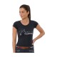 Eine Frau trägt ein enges schwarzes T-Shirt mit 'Shoes Equestrian' in glitzernden Buchstaben, kombiniert mit einem braunen Gürtel und dunklen Hosen.