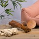 Ein Glasbehälter mit einem großen Hundekauartikel, einem rosa Haustierbett, einem Holzbrett und zwei verknoteten Seilspielzeugen auf einer Holzoberfläche.
