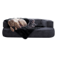 Ein großer, entspannter Hund und ein kleiner, flauschiger Hund sitzen auf einer plüschigen grauen Couch, die mit einer schwarzen Decke bedeckt ist.