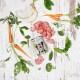 Een blik 'DOG'S LOVE' hondenvoer omringd door verse ingrediënten zoals stukjes kip, wortelen, broccoli en basilicum op een houten oppervlak.