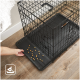 Eine Hand greift nach einer schwarzen Haustierbox mit einem abnehmbaren Tablett, auf dem kleine Haustierfutterstücke verstreut sind.