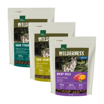 Drei Säcke von Real Nature's "Wilderness" Hundefutter: "Dark Fjord", "True Country" und "Rocky Hills", mit Wolf-Bildern und Nährwertinformationen.