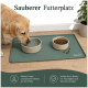 Draufsicht auf einen braunen Hund, der aus einer Wasserschüssel auf einer grünen Matte trinkt, mit Trockenfutter, Wasserspritzern und dem Logo 'Romneys'.