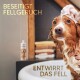 Ein nasser Hund mit Seifenschaum im Fell wird gebadet, mit Handtüchern im Hintergrund. Text lautet "Beseitigt Fellgeruch" und "Entwirrt das Fell."
