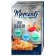 Kot wylegujący się obok pudełka "Moments to enjoy" z rybnym wyborem, zawierającym tuńczyka atlantyckiego i pacyficznego oraz tuńczyka z krewetkami.