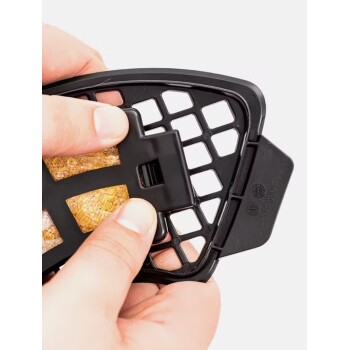 Eine Person hält einen schwarzen Leckerli-Halter für Haustiere mit einem strukturierten Leckerli darin und demonstriert, wie man ihn sichert.