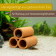 Drei Terrakotta-Röhren als Aquariumversteck mit Welsen und Tetras auf Sand; deutscher Text: 'Handgebrannter Ton – für Rückzug & Verstecke'.