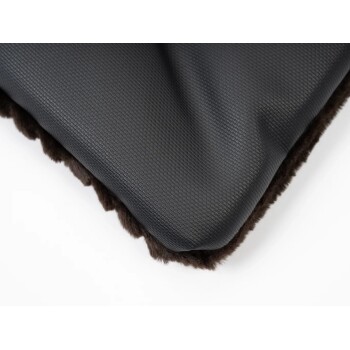 Schwarzes Haustierbett mit strukturierter Oberfläche und weichem braunem Fellfutter, teilweise sichtbar auf einem weißen Hintergrund.