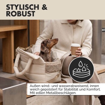 Nahaufnahme eines beigen gepolsterten Tierträgers mit „PAW WOW“-Etikett, beschrieben als stylisch, robust, wind- und wasserabweisend mit Metallbeschlägen.