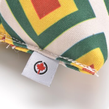 Nahaufnahme eines bunten Haustierspielzeugs mit geometrischem Muster in Grün, Gelb und Rot, mit einem Etikett mit einem kanadischen Ahornblatt-Logo.