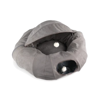 Graues rundes Katzenbett mit Haubenüberdachung, Tunnel-Eingang und hängenden weißen Bommelspielzeugen, Innenraum mit kuscheligem Kissen.