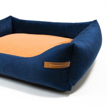 Dunkelblaue Haustierbett mit einem weichen orangefarbenen Zentrum, mit einem Lederschild, auf dem "RexProduct.com" steht.