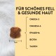 Ein 1 cm großer, knochenförmiger Leckerbissen für Haustiere auf einem hellgelben Hintergrund mit Zutaten und einer deutschen Überschrift für gesundes Fell und Haut.