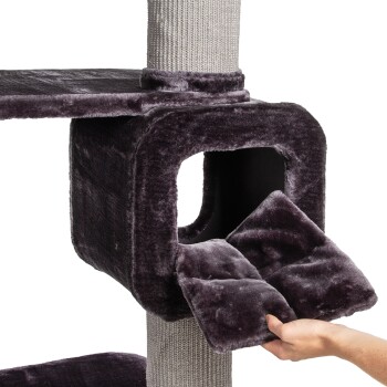 Eine Hand zieht ein plüschiges, abnehmbares Kissen aus einem dunkelvioletten Katzenbaum mit einem gemütlichen, würfelförmigen Versteck und einem strukturierten Kratzbaum.