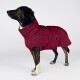 Gestromter Hund trägt burgunderfarbenen Fleece-Mantel mit hohem Kragen und Seitentasche, Label 'THE DOG', steht vor weißem Hintergrund.