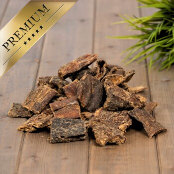 Premium Hundeleckerlis in verschiedenen Formen und Größen, auf einer Holzoberfläche mit einer grünen Pflanze im Hintergrund präsentiert.