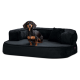 Ein schwarzer Dackel, der auf einem plüschigen, dunkelgrauen Hundebett mit erhöhten Seiten und einem kleinen Kissen entspannt.