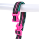 Eine bunte Haustierleine mit einem schwarz, pink und türkis gestreiften Design und einer pinken Kunststoffschnalle, die an einer weißen Stange hängt.