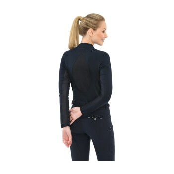 Eine Frau in einem enganliegenden schwarzen Langarmoberteil mit Netzdetails und dunklen Hosen, die mit dem Rücken zur Kamera steht.