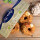 Eine Tüte mit Haustierleckereien, die mit "Premium Qualität" beschriftet ist, mit drei runden, knusprigen Hundesnacks auf einer Holzoberfläche, neben einem Seilspielzeug.